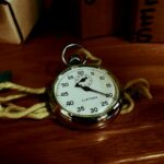 White Pocket Watch With Gold-colored Frame on Brown Wooden Board