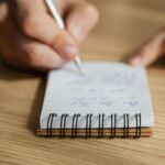 Crop man writing in notebook with pen