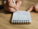 Crop man writing in notebook with pen