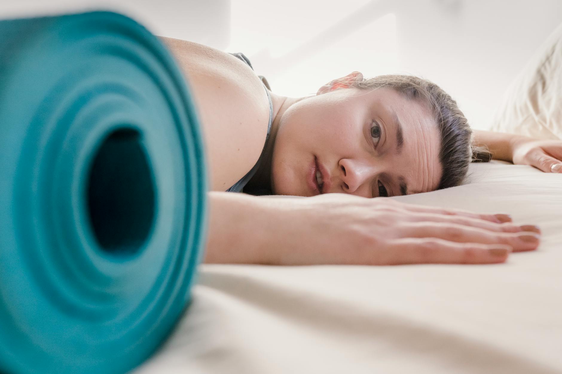 Tired woman lying on bed during workout