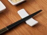 A Pair of Black Chopsticks on a White Chopstick Rest