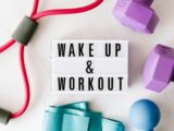 Wake up and workout title on light box surface surrounded by colorful sport equipment