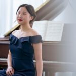 Elegant Asian female musician sitting near piano