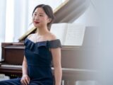 Elegant Asian female musician sitting near piano