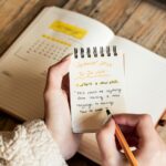 A person holding a pen and writing in a notebook