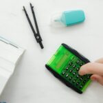 Person Using A Small Green and Black Calculator