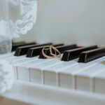 Golden rings on piano keyboard under veil with ornament during festive event in daytime