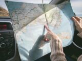 Person Wearing Beige Sweater Holding Map Inside Vehicle