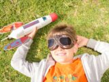 Boy Lying on Grass with His Rocket Toy