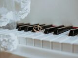 Golden rings on piano keyboard under veil with ornament during festive event in daytime