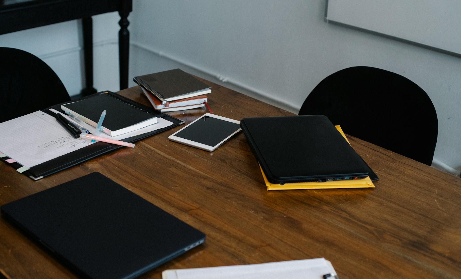 From above of modern laptop and tablet placed on wooden table with various notebooks in workplace