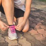 Woman Lacing Up Her Gray and Pink Nike Low-top Athletic Shoe