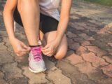 Woman Lacing Up Her Gray and Pink Nike Low-top Athletic Shoe