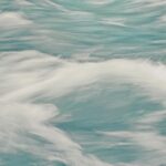 Abstract background of clear waves of sea rolling fast creating white foam in motion