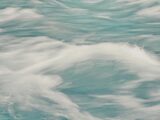 Abstract background of clear waves of sea rolling fast creating white foam in motion