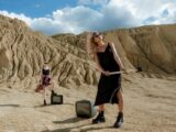 Blonde Women with Sunglasses Posing on Desert with Sledgehammer