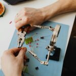 Hands of Person Assembling Transistors with Use of Magnifying Glass