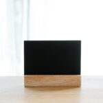 Empty black name card on wooden holder placed on desk in modern workplace