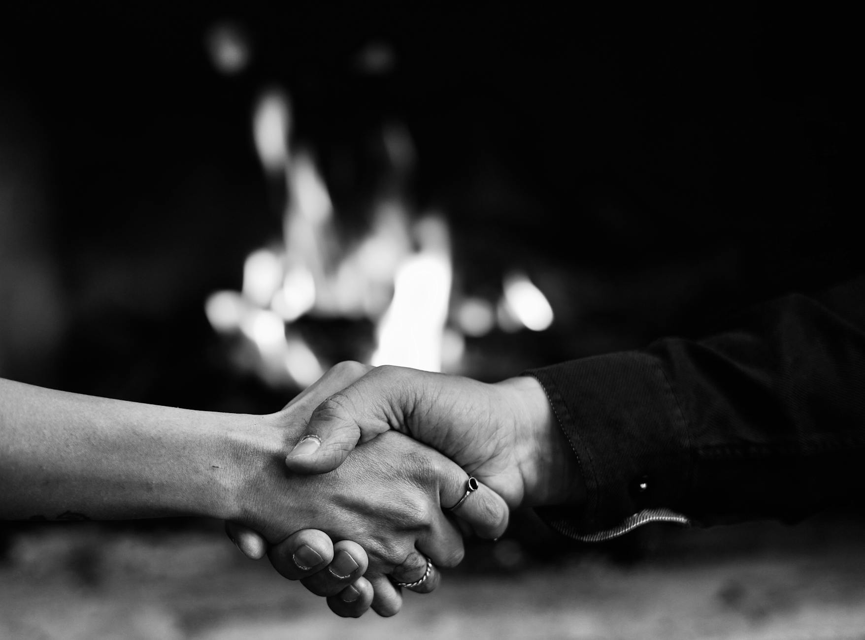 Two people shaking hands in front of a fireplace