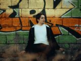 A man sitting on a bench in front of a graffiti wall