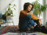 Lady sitting near paintings on floor in studio