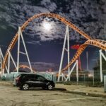 A Black Car Parked Near the Rollercoaster Railings