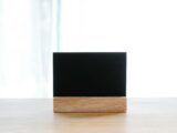 Empty black name card on wooden holder placed on desk in modern workplace