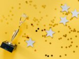 Golden Statuette and Stars on Yellow Background