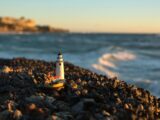 Close-up of Lighthouse Figurine on Rocks on the Beach