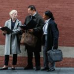 Serious diverse partners examining documents together on city street